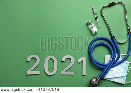 Flat Lay Composition With Coronavirus Vaccine On And Number 2021 Green Background, Space For Text