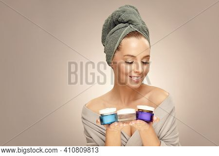 Beauty Portrait, Smiling Woman Holds Various Skin Creams On Beige Isolated.