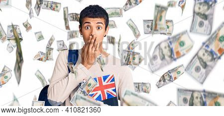 Young african amercian man wearing student backpack holding binder and uk flag covering mouth with hand, shocked and afraid for mistake. surprised expression