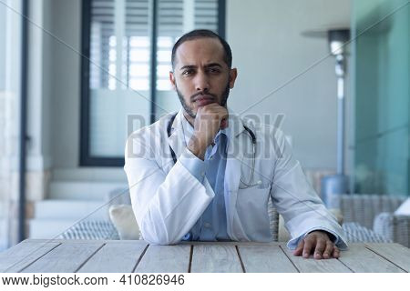 Portrait of caucasian male doctor looking at the camera and rubbing his chin. professional medical worker wearing stethoscope and lab coat.