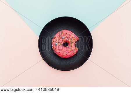Pink Donut On A Black Plate On A Multicolored Background Of Blue And Pink