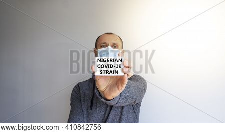 Covid-19 Nigerian Strain Symbol. White Card, Words 'nigerian Strain'. A Young Man In A Grey Wear And