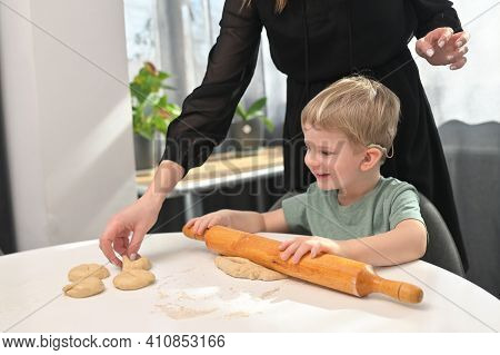 Mother With Toddler Son With Cochlear Implants Baking Donuts On Kitchen