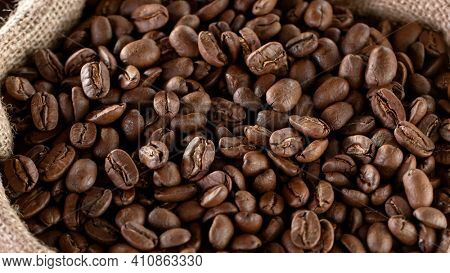 Falling Roasted Coffee Beans into Jute Bag, close-up.