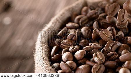 Falling Roasted Coffee Beans into Jute Bag, close-up.