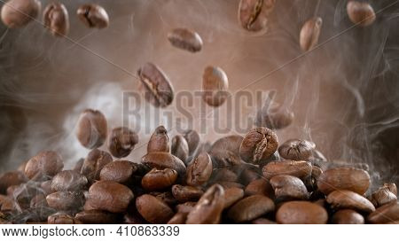 Falling Roasted Coffee Beans on Brown Background, close-up.