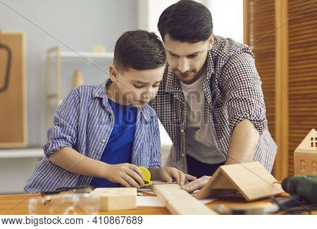 Happy Concentraited Father And Son Measuring Wooden Details For Making Birdhouse