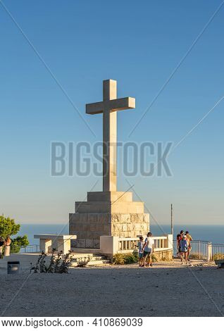 Dubrovnik, Croatia - Aug 21, 2020: Tourists At Top Of Mountain Srd With White Cross In Sunset