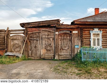 VISIM, RUSSIA - JUNE 22, 2015. Village street in summer. Historical wooden house with rickety carved gate. Village of Visim, Sverdlovsk region, Urals, Russia