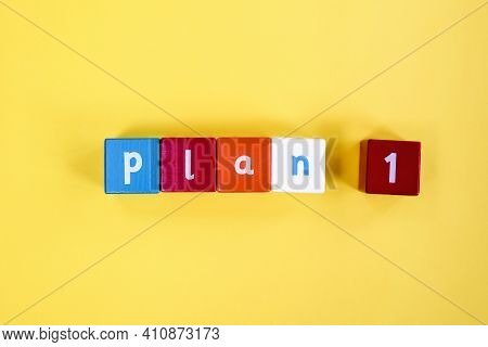 Word Plan 1 Made From Colored Wooden Blocks. Painted Cubes With Letters On Yellow Background. Concep