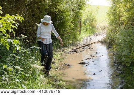 Fit Indian Woman Hiking On A Flooded Trail Or Path In English Countryside, Uk