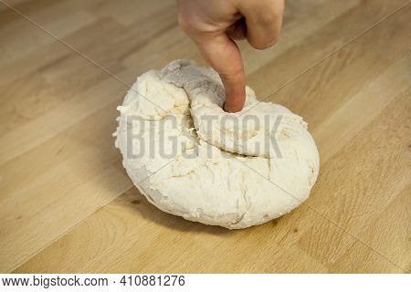 Freshly Kneaded Hard Unripened Wheat Dough On A Wooden Table With The Hand On Top. Preparation Of Do