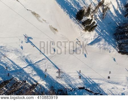 Snowboarders And Skiers Drive Down Ski Slope In Winter Through Fresh Snow, Areal Top View