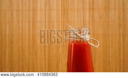 Bottle Of Tomato Juice On Wooden Background. Bottle Neck With Twine Bow