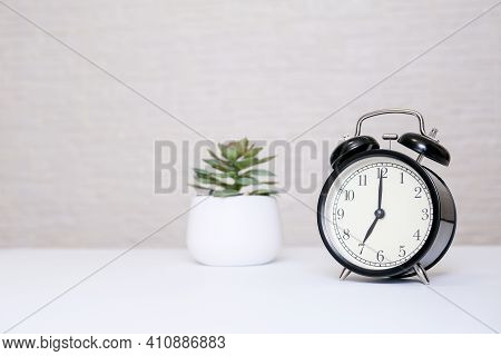 An Alarm Clock Showing 7 Oclock Standing On A White Table With Copy Space, Everyday Shedule And Morn