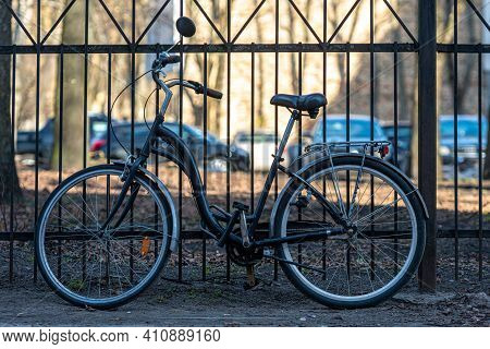 Vintage City Bicycle Parken Against A Metal Fence On A Sunny Day
