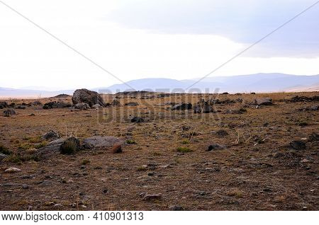 Remains Of An Ancient Stone Structure In The Autumn Steppe At The Foot Of The Mountain Range.