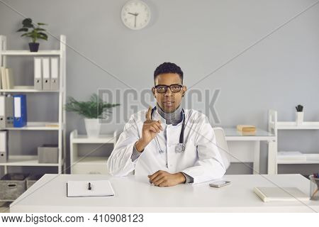 Young Serious Arfican American Man Doctor Therapist Gesticulating During Videocall