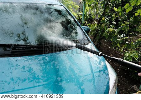 Car Wash At Home Alone. Car Wash High Pressure Close-up. A Man Washes A Green Car.