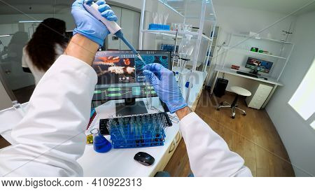 Pov Of Scientist Using Micropipette In Lab To Extract Blue Liquide From Test Tubes Analysing Chemica