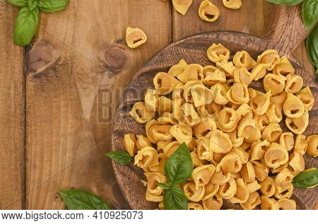 Tortellini Mignon On A Wooden Board With Basil And Parmesan. Specialties Of The Cuisine From Bologna