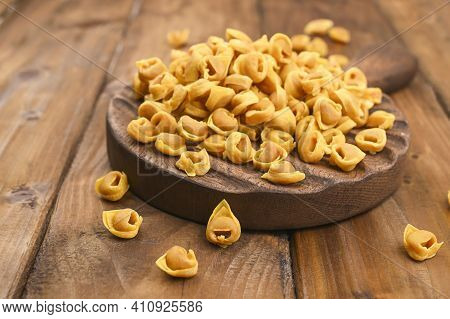 Tortellini Mignon On A Wooden Board And Parmesan. Specialties Of The Cuisine From Bologna And Emilia
