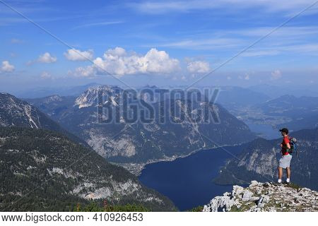 Young Man In Red T-shirt And Black Cap On His Head, Standing Over Abyss, Staring At Austrian Hallsta