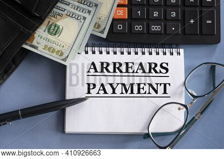 Arrears Payment - Words In A Notebook Against The Background Of Money, Glasses And Calculator. Educa