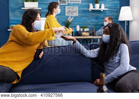 Group Of Multi Ethnic Using Hand Sanitizer To Prevent Coronavirus Spread While Spending Time Togethe