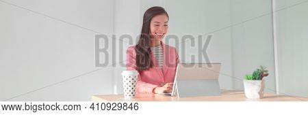 Working from home office Asian business woman using laptop for videocall or banking financial services wearing professional suit for live stream videoconference. Panoramic banner.