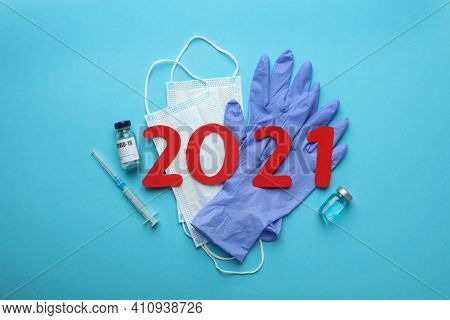 Flat Lay Composition With Coronavirus Vaccine And Number 2021 On Light Blue Background