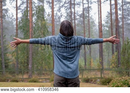 Happy Woman Spread Her Arms To The Sides And Enjoys The Warm Rain, Looking At The Pine Forest. Unity