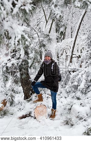 Smiling Young Woman Standing On Fallen Tree After Sleet Load And Snow In A Snow-covered Winter Park.