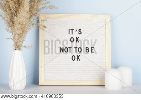 Dried Pampas Grass In Vases, Candles And Felt Letter Board With Phrase It Is Ok Not To Be Ok On Blue