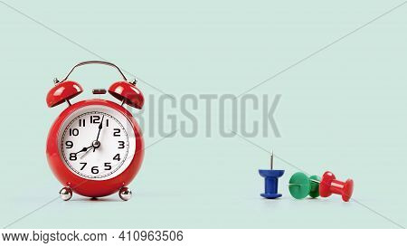 Red Alarm Clock On Green Office Or Home Desk With Several Multicolor Drawing Or Push Pins With One S