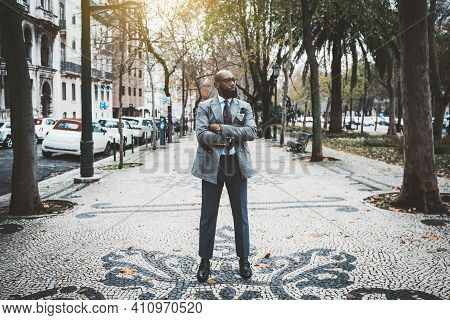 A Stately Mature Hairless Barbate Black Man Entrepreneur In A Dapper Custom Made Suit Is Standing Wi