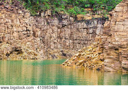 Beautiful Landscape With Sedimentary Rock Walls With Golden Tones And The Water Of The Lake Between 