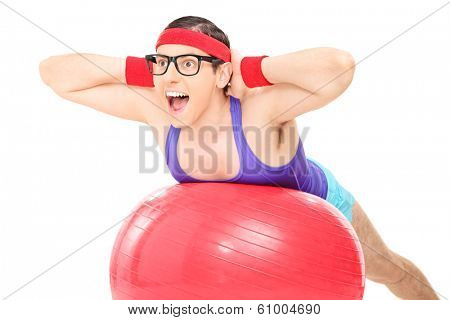 Nerdy guy doing an exercise on a pilates ball isolated on white background