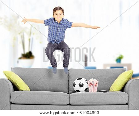 Overjoyed boy jumping on couch at home shot with tilt and shift lens