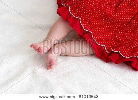 Newborn baby girl feet in red dress
