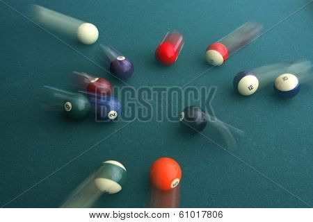 Green pool table with balls in motion