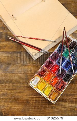 Composition with colorful watercolors, brushes and sketcher on wooden background 