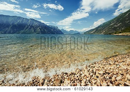 Italian mountain Garda lake with pebble beach in summer