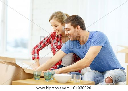 repair, building and home concept - smiling couple unpacking kitchenwear