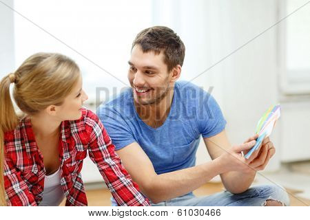 repair, interior design, building, renovation and home concept - smiling couple looking at color samples at home