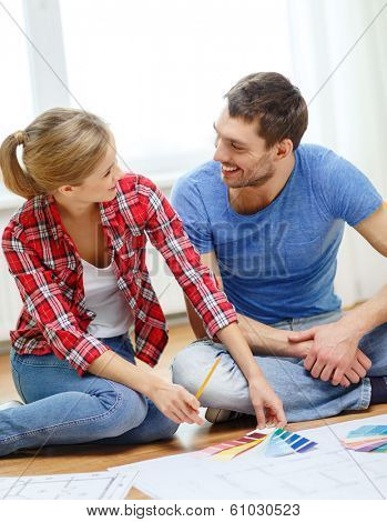 repair, interior design, building, renovation and home concept - smiling couple looking at color samples at home