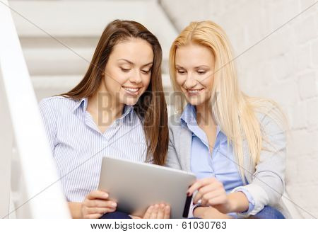 business, technology and startup concept - smiling creative team with tablet pc computer sitting on staircase