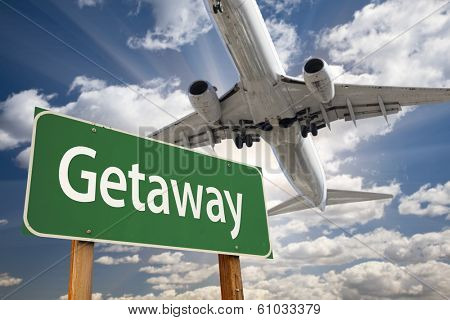 Getaway Green Road Sign and Airplane Above with Dramatic Blue Sky and Clouds.