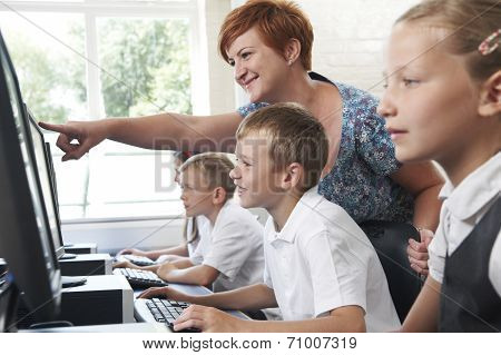 Male Elementary Pupil In Computer Class With Teacher