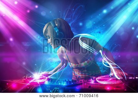 Energetic Dj girl mixing music with powerful light effects